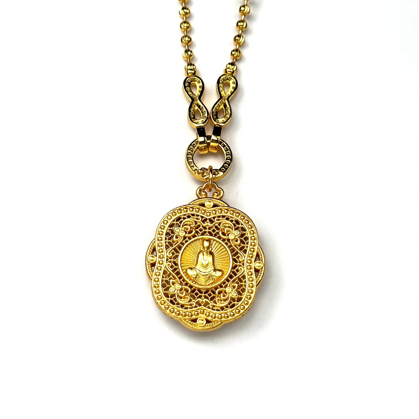 The reversible back side of a sand gold mandala pendant, showcasing a central engraved seated Buddha with a radiant sunburst halo on a geometric openwork lattice background.