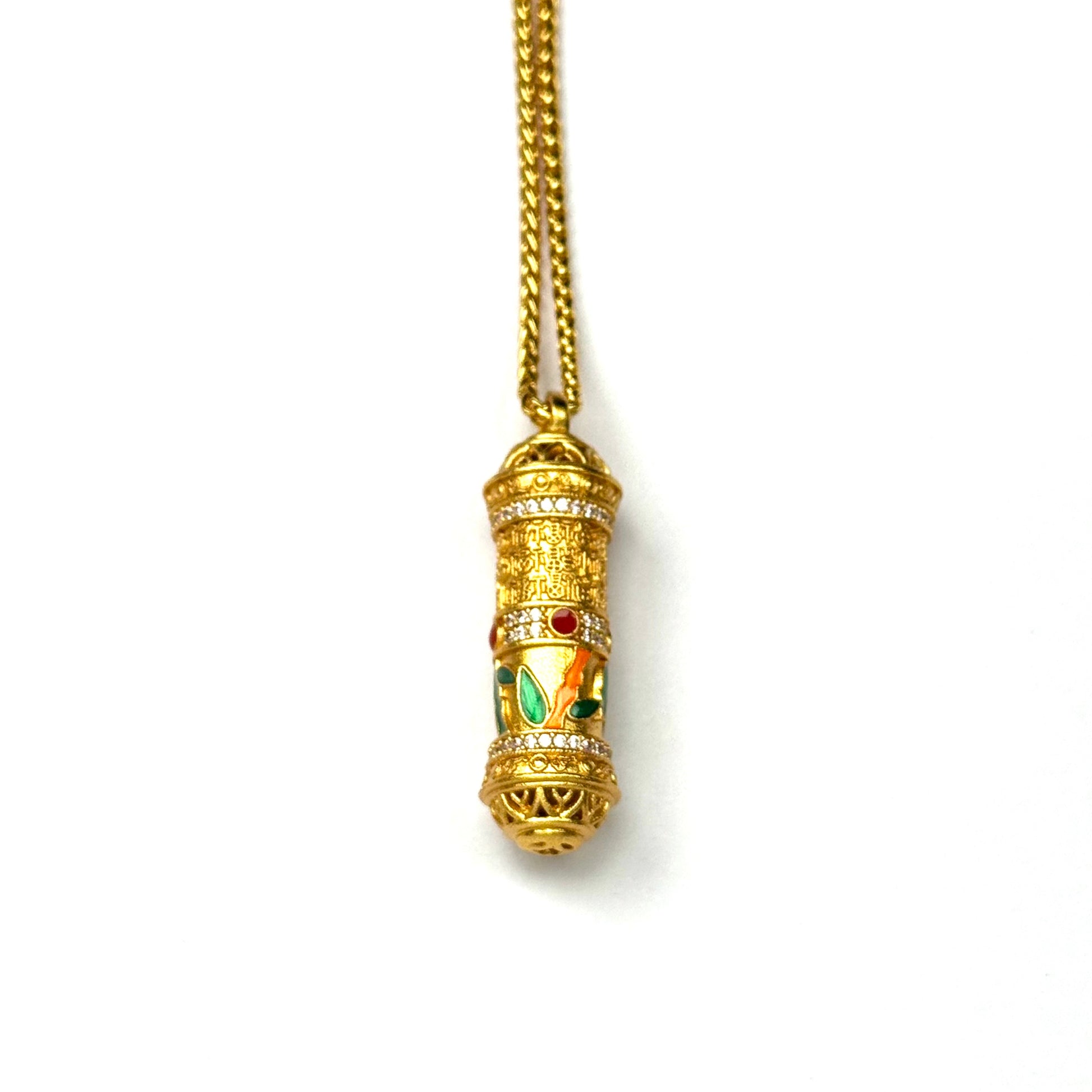 A front view of a premium sand gold spinning prayer wheel pendant featuring engraved blessing scriptures and colorful enamel leaves on a white background.
