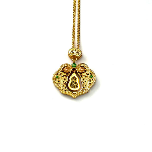 The back side of a sand gold longevity lock necklace, showcasing the finely brushed gold texture and the reverse view of the central green gemstone gourd.