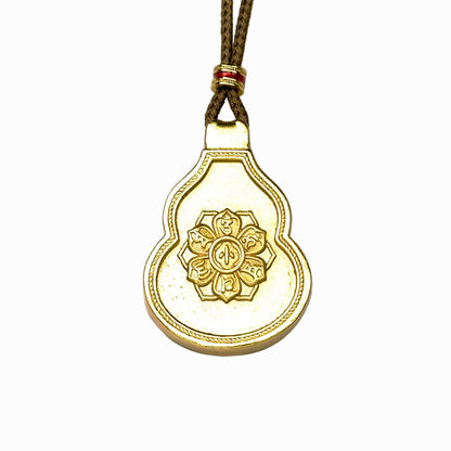 The reversible back side of a sand gold Hulu gourd pendant, showcasing an embossed six-syllable mantra lotus wheel motif on an antique matte gold background.