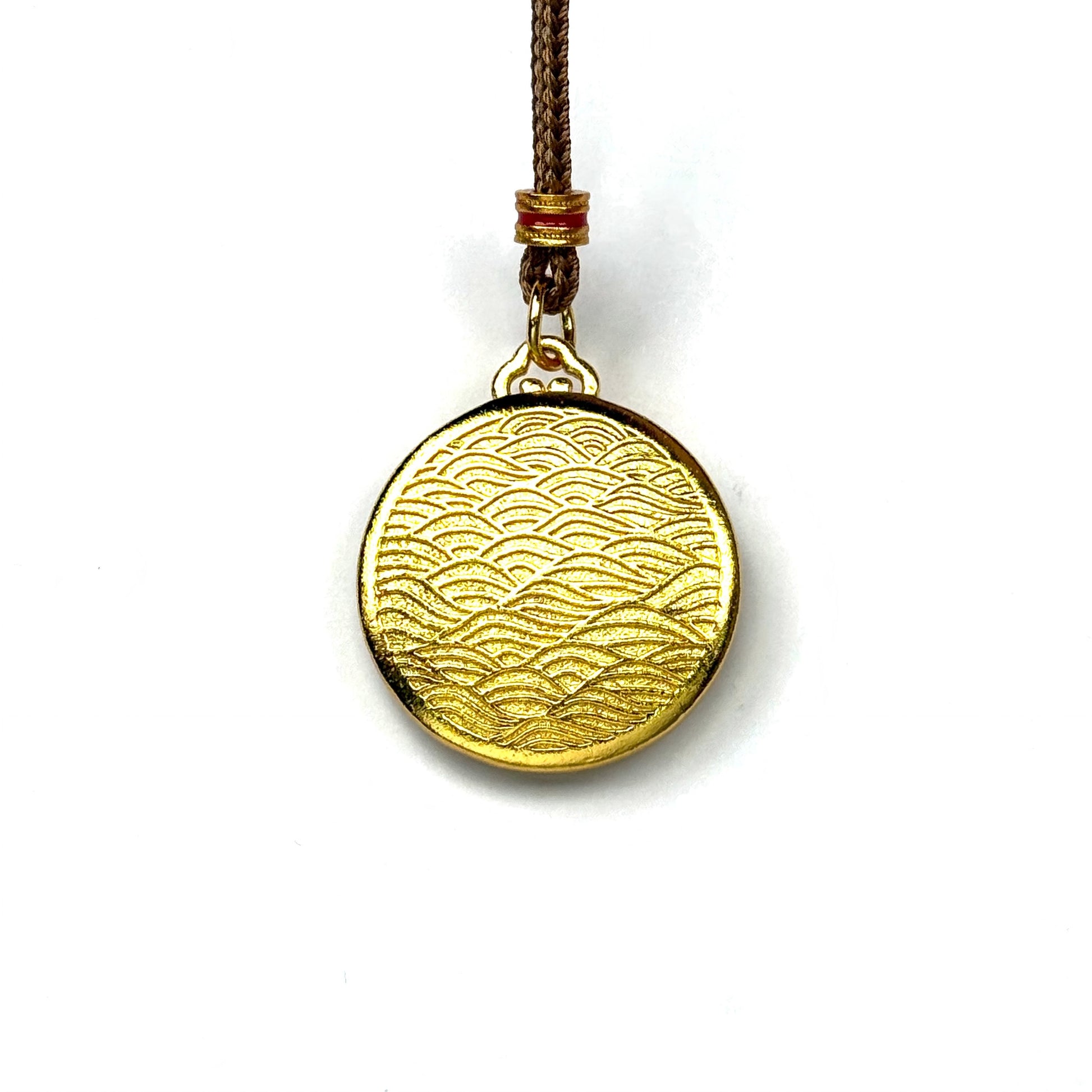 The reversible back side of a sand gold round charm, featuring a deeply engraved traditional Chinese ocean wave geometric pattern on a white background.