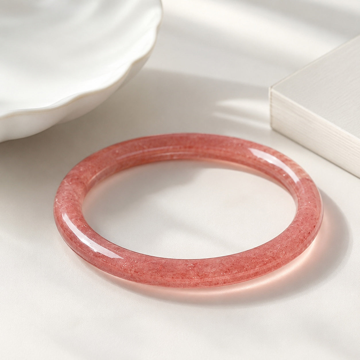 Polished strawberry quartz bangle bracelet in warm natural light