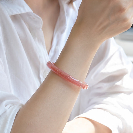 Woman wearing a rosy pink strawberry quartz bangle bracelet
