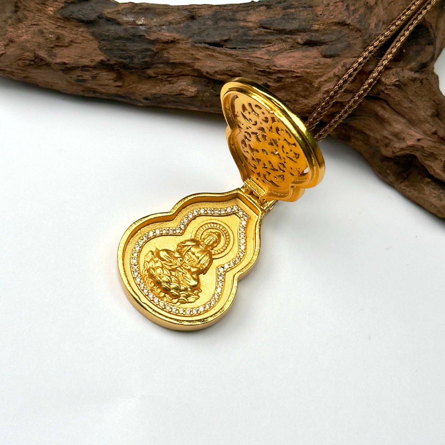 An elegant side-angled shot of the opened sand gold Hulu locket on wood, capturing the hidden protective deity altar inside the gourd shell.