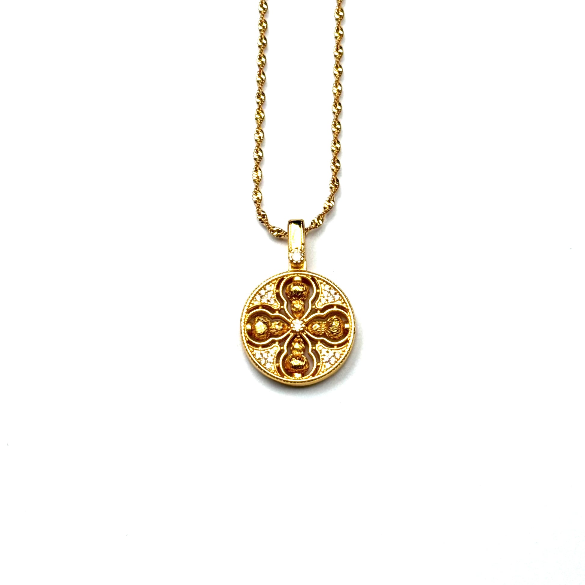A front view of an authentic sand gold crossed Vajra pendant featuring a brilliant crystal rhinestone pavé background on a gold chain, displayed against a white background.