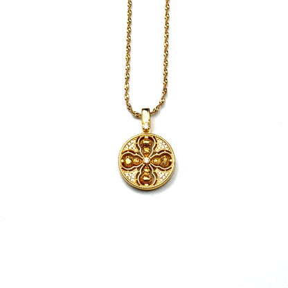 A front view of an authentic sand gold crossed Vajra pendant featuring a brilliant crystal rhinestone pavé background on a gold chain, displayed against a white background.