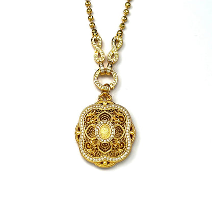 A crisp front view of an authentic sand gold round pendant featuring a detailed filigree lotus motif and a brilliant double-row rhinestone border connected to a paved infinity clasp on a white background.