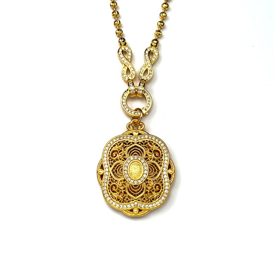 A crisp front view of an authentic sand gold round pendant featuring a detailed filigree lotus motif and a brilliant double-row rhinestone border connected to a paved infinity clasp on a white background.