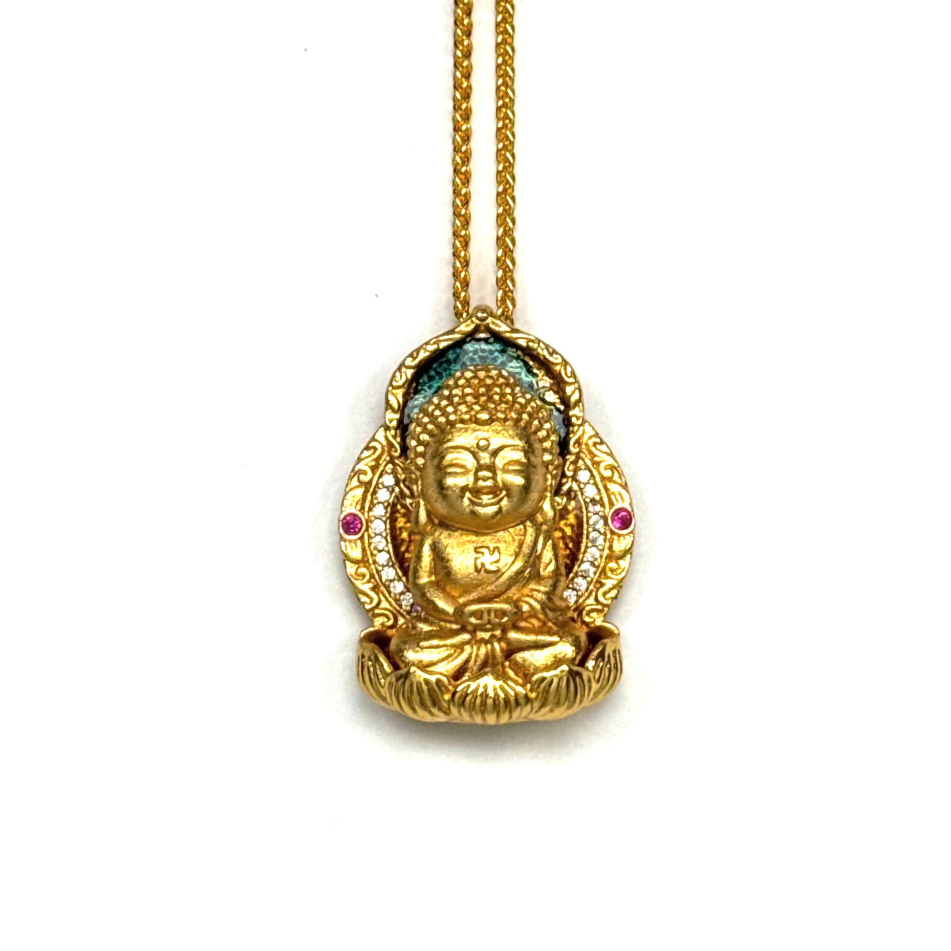 A front-view close-up of an authentic sand gold seated Buddha pendant, featuring a Swastika symbol, blue enamel halo, and pink accent stones on a gold chain against a white background.