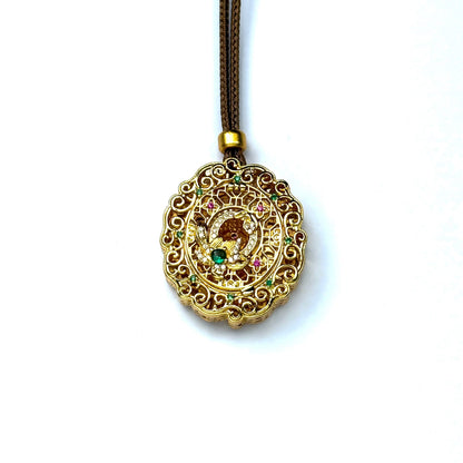 A front view of a closed round sand gold locket pendant, showcasing intricate openwork filigree and colorful micro gemstone accents on a white background.