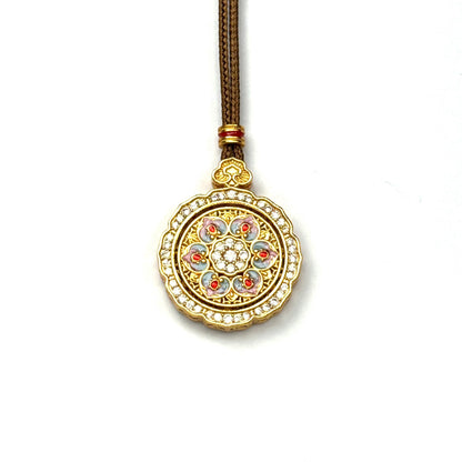 A front view of a sand gold spinning lotus pendant featuring pastel pink and blue enamel detailing with a sparkling rhinestone border on a white background.