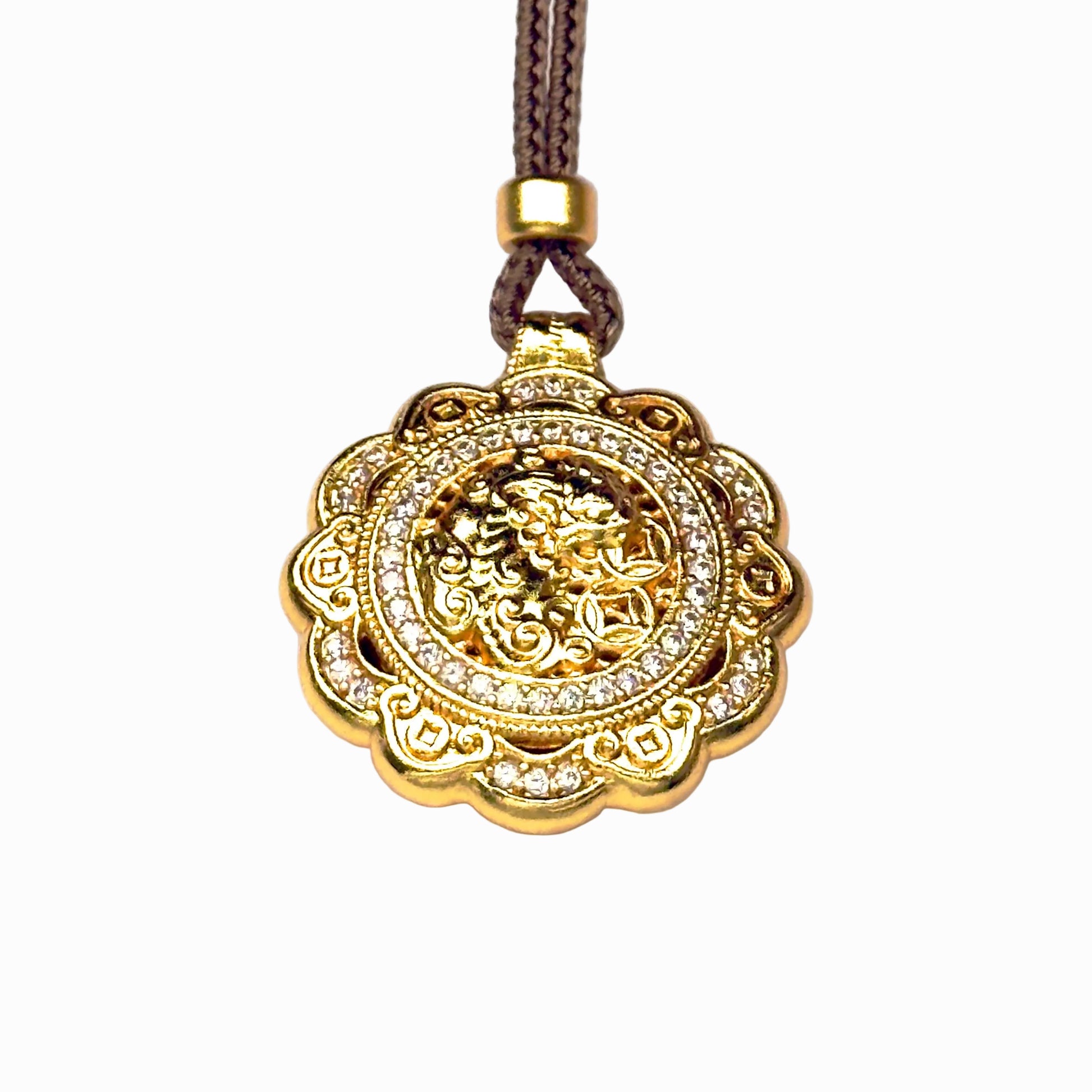 A front view of an authentic sand gold spinning Pixiu pendant featuring a detailed 3D embossed wealth beast holding fortune coins and a brilliant rhinestone border on a white background.