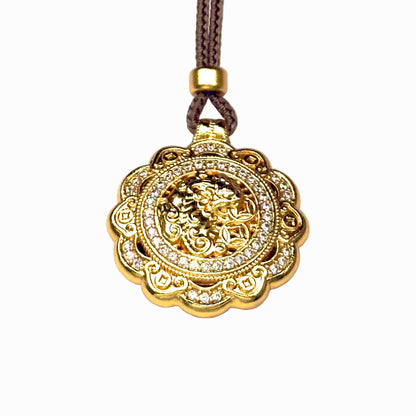 A front view of an authentic sand gold spinning Pixiu pendant featuring a detailed 3D embossed wealth beast holding fortune coins and a brilliant rhinestone border on a white background.