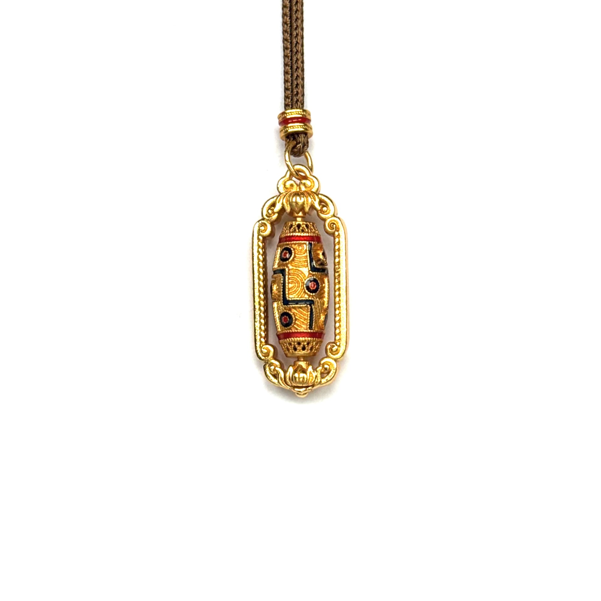 Close-up of a traditional Tibetan style spinning prayer wheel necklace with beautiful enamel geometric patterns.