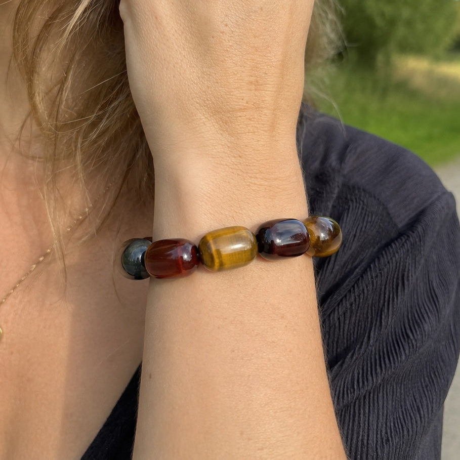 Woman wearing a tricolor tiger’s eye barrel bead bracelet outdoors