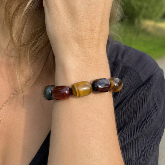 Woman wearing a tricolor tiger’s eye barrel bead bracelet outdoors