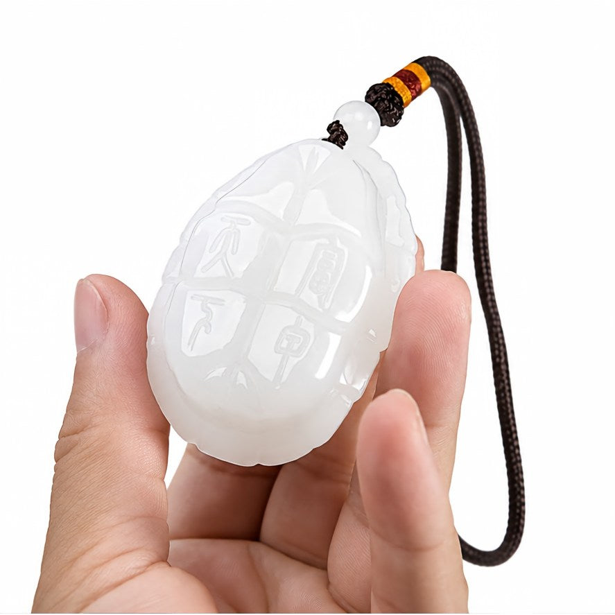 White jade turtle amulet held in hand, showing the Fu Jia Tian Xia carving and scale