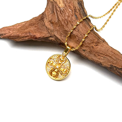 Top-down macro shot of a luxurious sand gold crossed Vajra necklace with sparkling crystal inlay displayed elegantly on rustic wood.