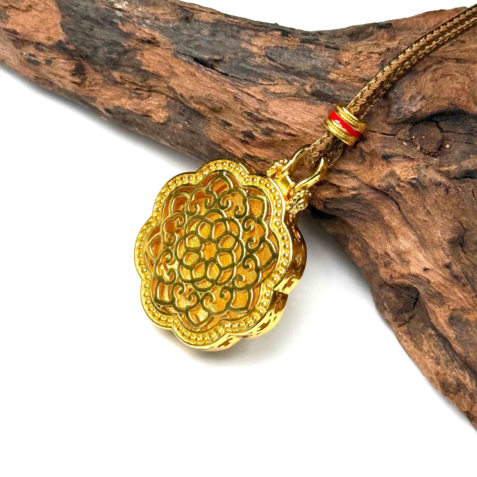 Macro angled shot of the embossed all-gold openwork filigree back side of a round protective talisman resting against natural rustic wood.