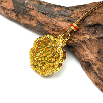 Macro angled shot of the embossed all-gold openwork filigree back side of a round protective talisman resting against natural rustic wood.