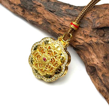 A luxurious sand gold fortune wheel pendant with shimmering red gemstones resting elegantly on rustic driftwood for a high-end Zen aesthetic.
