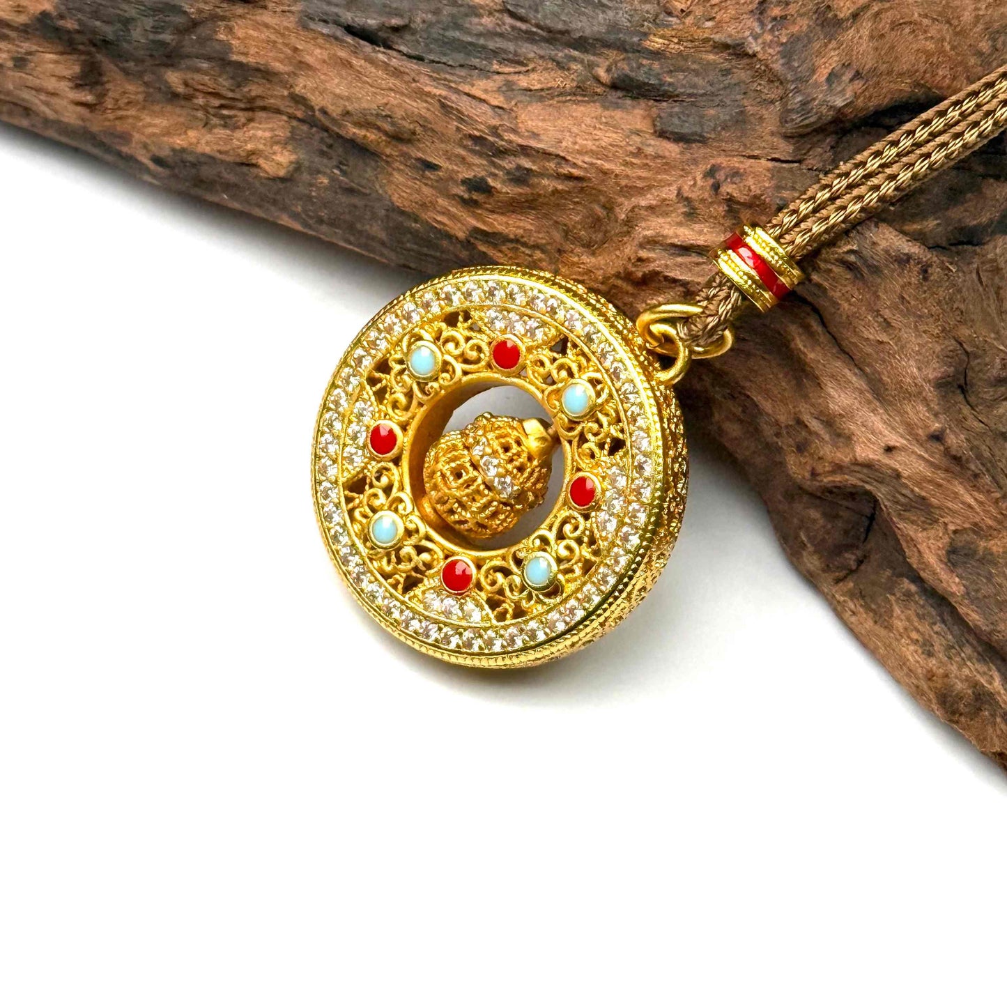 An elegant sand gold kinetic abundance talisman pendant with a 3D rotating center orb resting gracefully against natural rustic driftwood background.