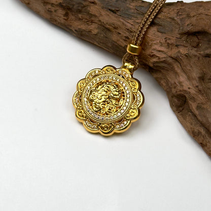 The beautifully textured filigree back side of a sand gold spinner pendant displaying the prosperity glyphs elegantly on a natural wood backdrop.