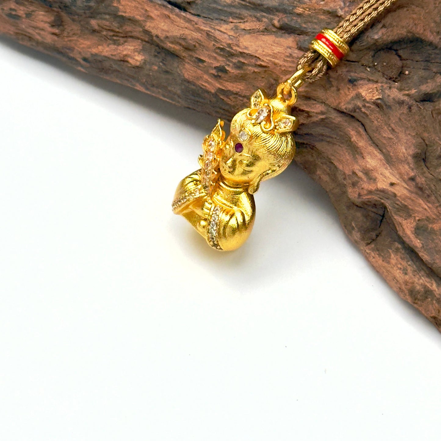 Macro close-up shot of an ancient style brushed sand gold Buddha deity charm resting against wood, capturing the precise rhinestone pavé rows.