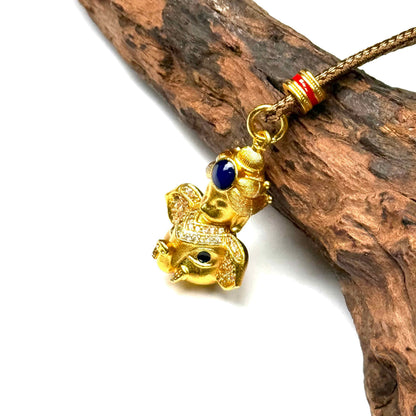 Close-up angled shot of a beautiful sand gold elephant deity pendant on driftwood, capturing the sparkling rhinestones and rich golden luster.