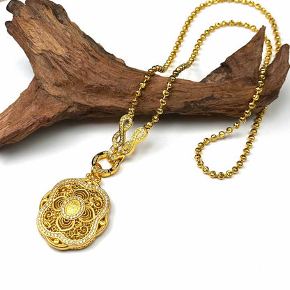 A luxurious sand gold infinity lotus talisman pendant with a heavy gold bead chain displayed elegantly against natural rustic wood for a serene Zen look.