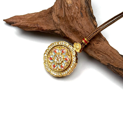 A close-up side angle of a rotating sand gold mandala pendant, demonstrating its smooth 360-degree spinning mechanism on wood.