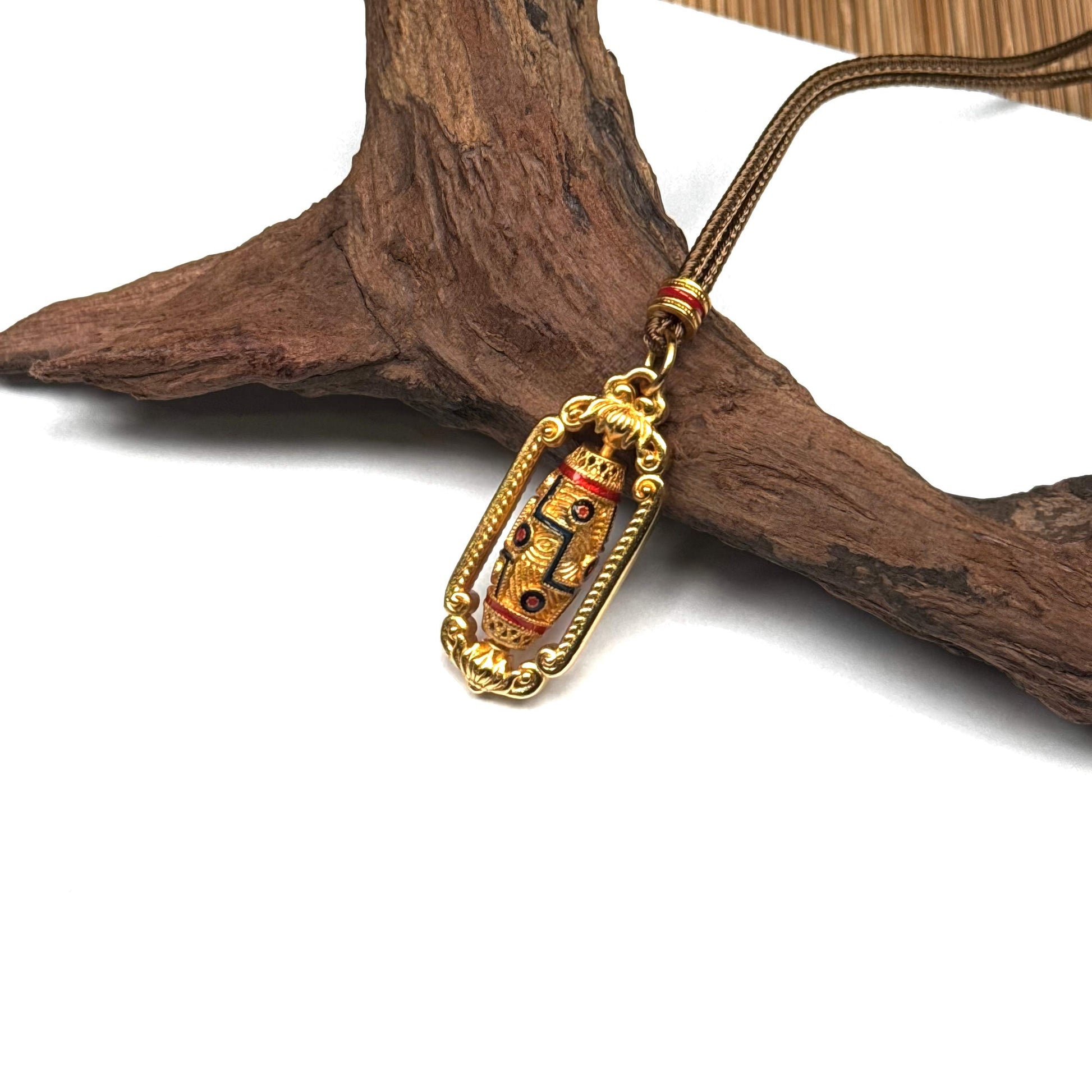 An elegant gold spinning Dzi bead amulet resting on rustic driftwood, showcasing its vintage craftsmanship and spiritual Zen aesthetic.