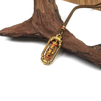 An elegant gold spinning Dzi bead amulet resting on rustic driftwood, showcasing its vintage craftsmanship and spiritual Zen aesthetic.